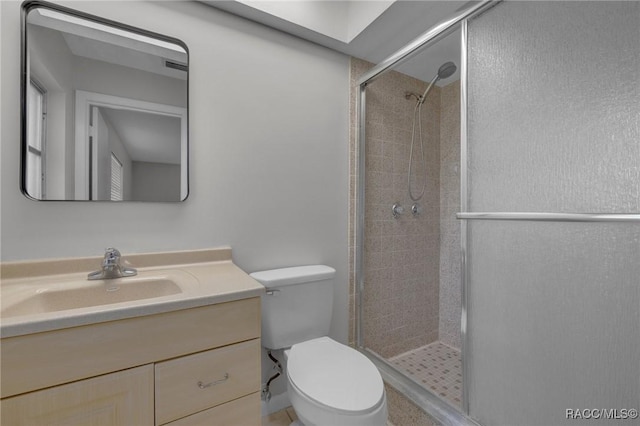 bathroom featuring toilet, a stall shower, and vanity