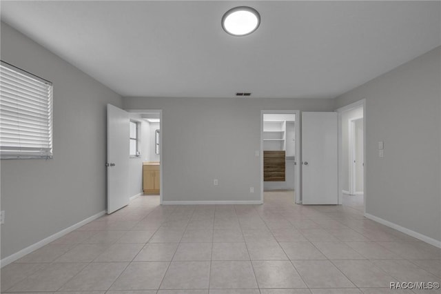 unfurnished room featuring light tile patterned flooring, visible vents, and baseboards