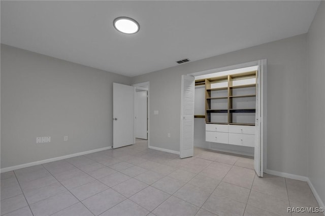 unfurnished bedroom with light tile patterned floors, baseboards, visible vents, and a closet