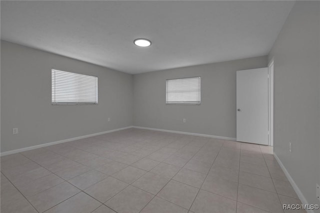 empty room featuring light tile patterned flooring and baseboards