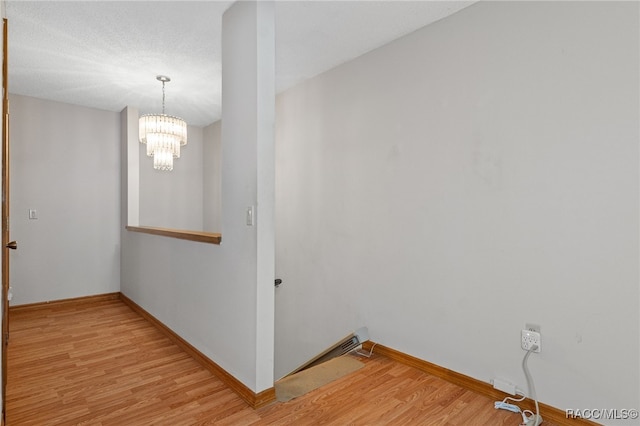 hall with light hardwood / wood-style floors and a notable chandelier