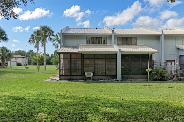 rear view of house featuring a sunroom and a lawn