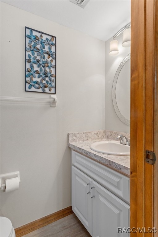 bathroom featuring hardwood / wood-style floors, vanity, and toilet