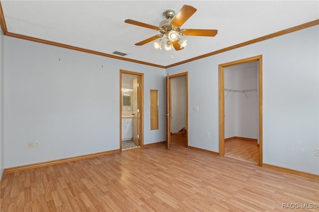 unfurnished bedroom with connected bathroom, light hardwood / wood-style floors, a spacious closet, and ceiling fan