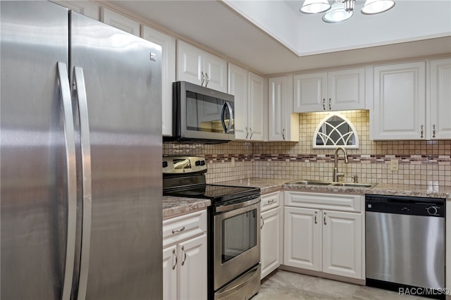 kitchen with light stone countertops, sink, stainless steel appliances, backsplash, and white cabinets