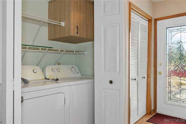 clothes washing area featuring washer and dryer, light hardwood / wood-style flooring, and cabinets