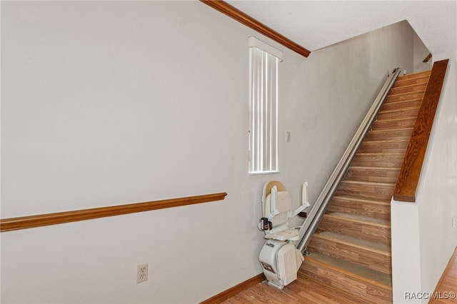 stairway featuring wood-type flooring and crown molding