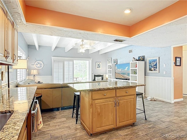857 N Palm Springs Ter, Crystal River, FL 34429 - kitchen with open floor plan, a breakfast bar area, light wood-type flooring, a wainscoted wall, and a ceiling fan