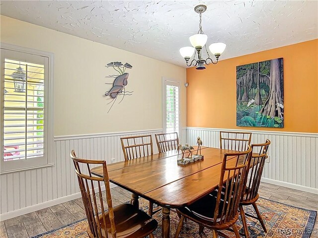 857 N Palm Springs Ter, Crystal River, FL 34429 - dining space with wood finished floors, a wainscoted wall, a chandelier, a textured ceiling, and baseboards