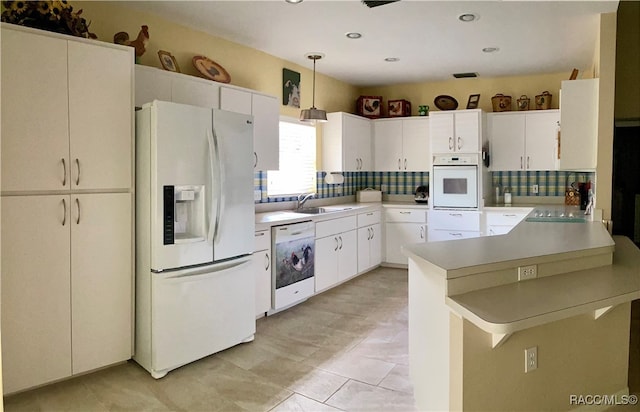 kitchen with hanging light fixtures, tasteful backsplash, kitchen peninsula, white appliances, and white cabinets