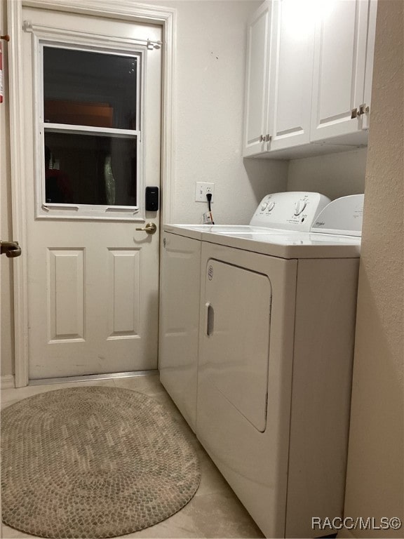 clothes washing area featuring light tile patterned flooring, cabinets, and separate washer and dryer