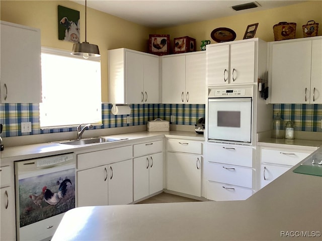 kitchen featuring decorative light fixtures, white cabinetry, white appliances, and sink