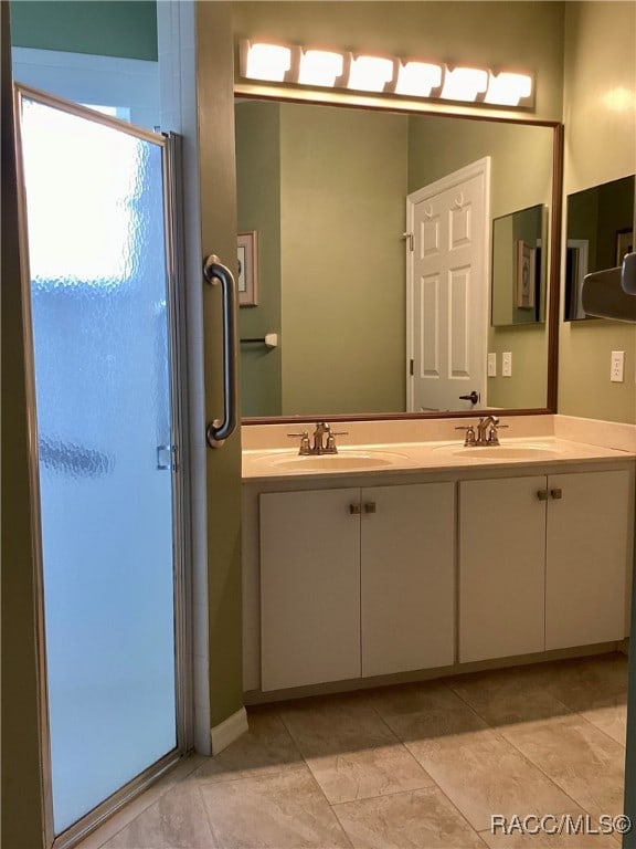 bathroom featuring tile patterned flooring, vanity, and a shower with shower door