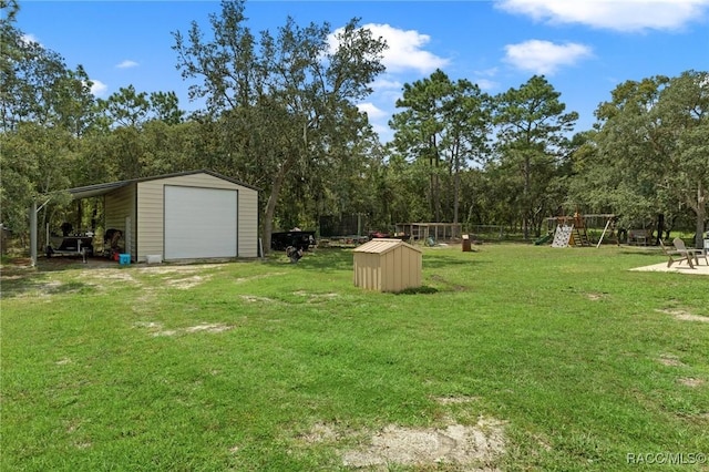 view of yard featuring a playground, a garage, and an outdoor structure