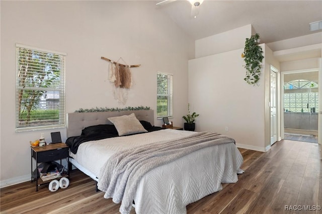 bedroom with multiple windows, hardwood / wood-style floors, and high vaulted ceiling