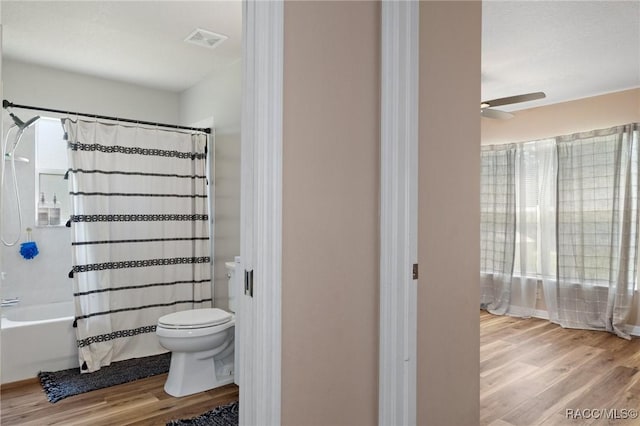 bathroom featuring ceiling fan, hardwood / wood-style flooring, toilet, and shower / bath combo