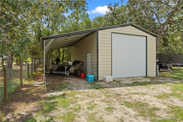 view of outdoor structure with a trampoline, a garage, and a carport