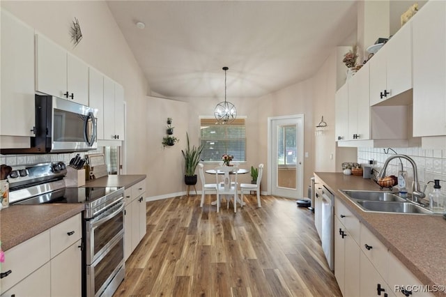 kitchen featuring stainless steel appliances, decorative light fixtures, sink, and white cabinets