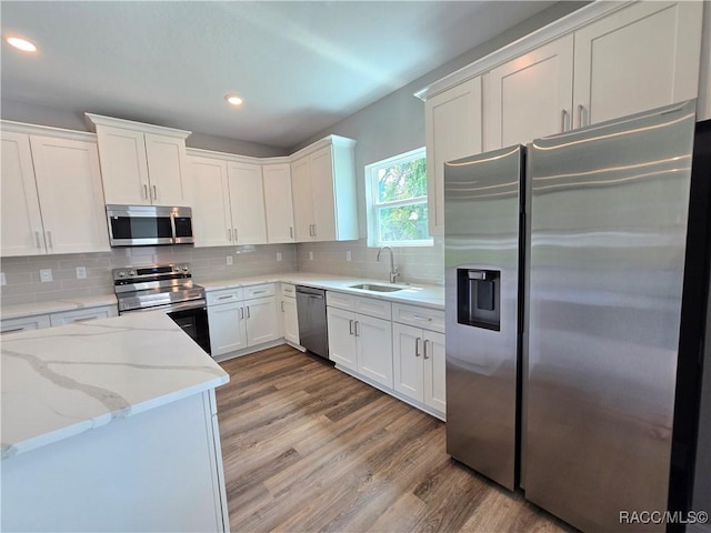 8 Calendula Ct, Homosassa, FL 34446 - kitchen featuring stainless steel appliances, a sink, white cabinets, light wood-style floors, and tasteful backsplash