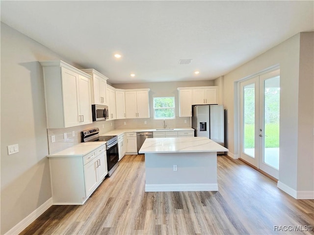 8 Calendula Ct, Homosassa, FL 34446 - kitchen with stainless steel appliances, a center island, light wood finished floors, tasteful backsplash, and white cabinets