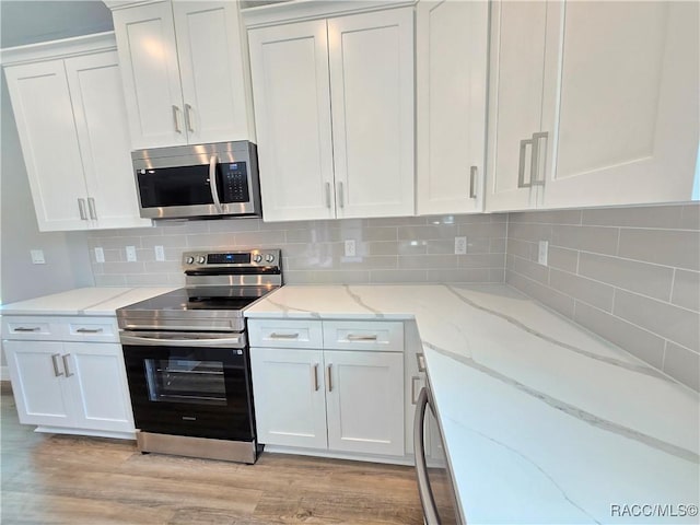 8 Calendula Ct, Homosassa, FL 34446 - kitchen with stainless steel appliances, white cabinetry, light wood finished floors, and tasteful backsplash