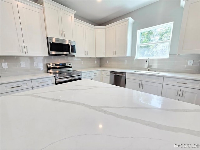 8 Calendula Ct, Homosassa, FL 34446 - kitchen with appliances with stainless steel finishes, a sink, white cabinetry, tasteful backsplash, and light stone countertops