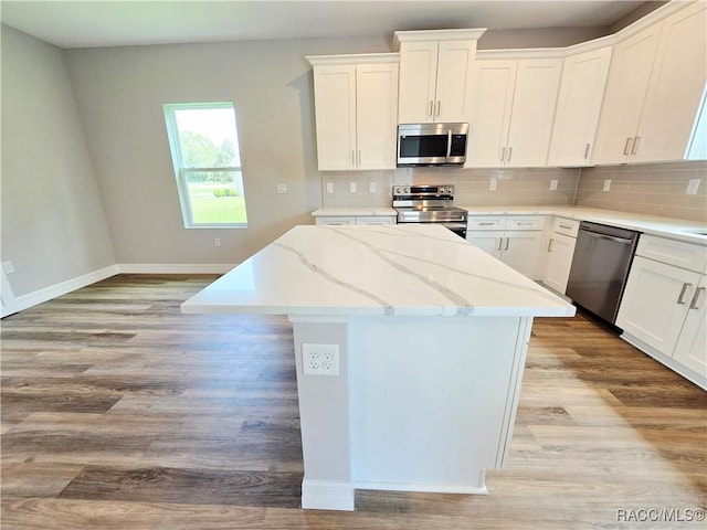 8 Calendula Ct, Homosassa, FL 34446 - kitchen with appliances with stainless steel finishes, a center island, light wood-style flooring, baseboards, and backsplash