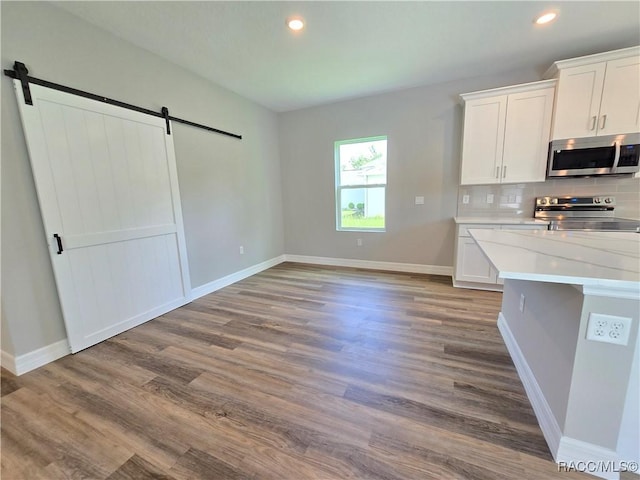8 Calendula Ct, Homosassa, FL 34446 - kitchen featuring appliances with stainless steel finishes, a barn door, white cabinets, wood finished floors, and recessed lighting