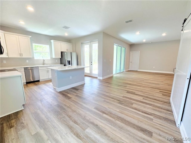 8 Calendula Ct, Homosassa, FL 34446 - kitchen with appliances with stainless steel finishes, a kitchen island, a barn door, open floor plan, and white cabinetry
