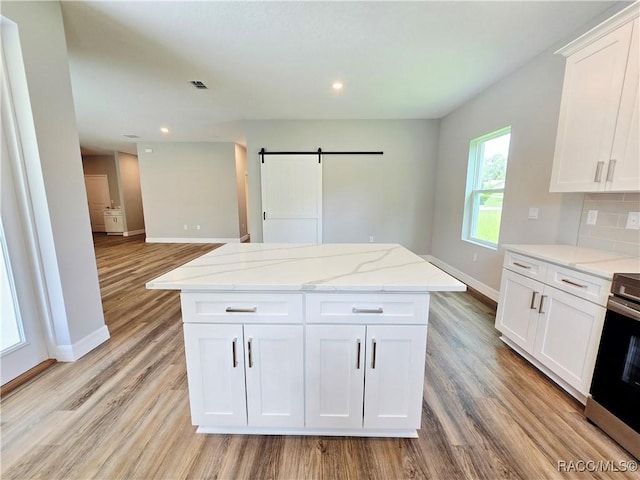 8 Calendula Ct, Homosassa, FL 34446 - kitchen featuring a barn door, baseboards, light wood finished floors, stainless steel stove, and white cabinetry