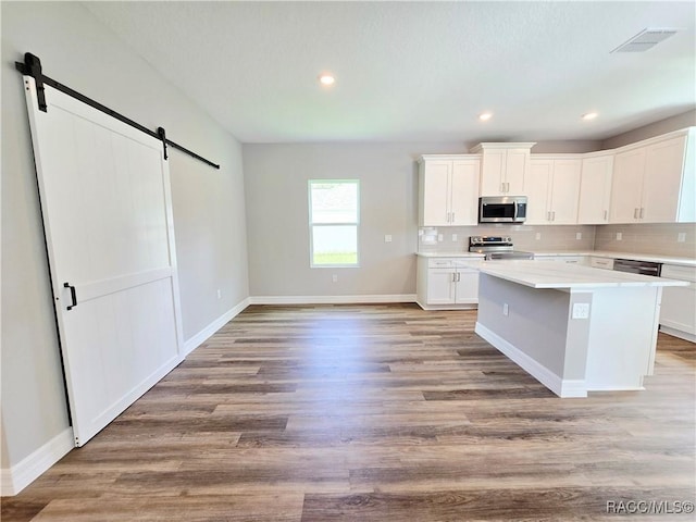 8 Calendula Ct, Homosassa, FL 34446 - kitchen featuring appliances with stainless steel finishes, a barn door, a kitchen island, white cabinetry, and light countertops