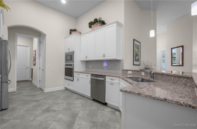 kitchen with white cabinets, sink, hanging light fixtures, light stone counters, and stainless steel appliances