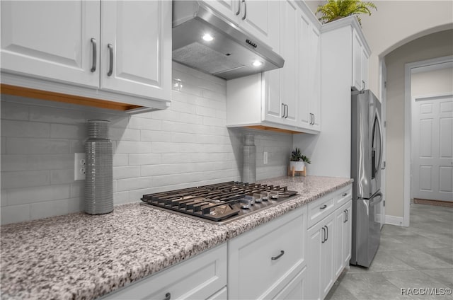 kitchen featuring decorative backsplash, light stone counters, white cabinets, and appliances with stainless steel finishes