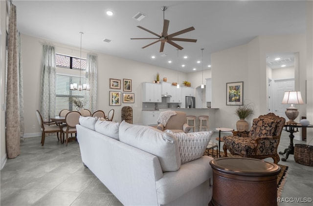 living room with light tile patterned floors and ceiling fan with notable chandelier