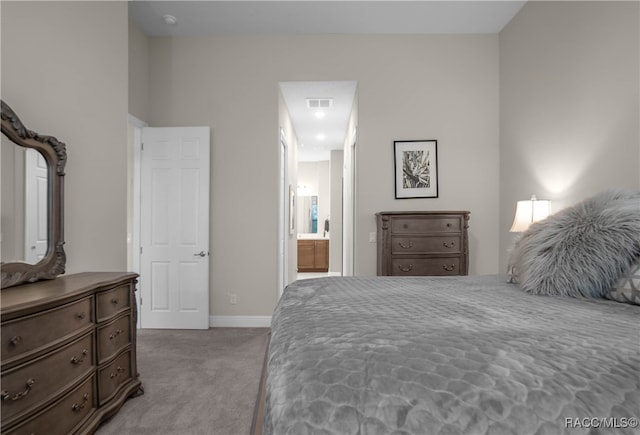 bedroom with ensuite bathroom and light colored carpet