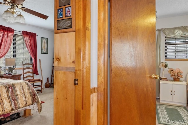 bedroom with a textured ceiling, ceiling fan, and light carpet