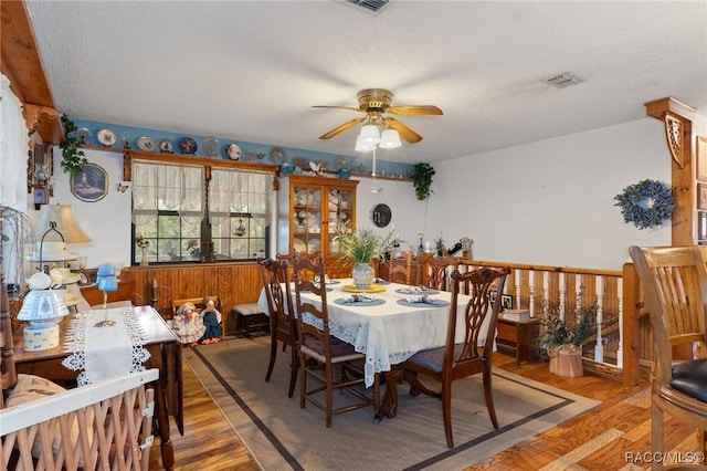 dining area with wood-type flooring, a textured ceiling, and ceiling fan