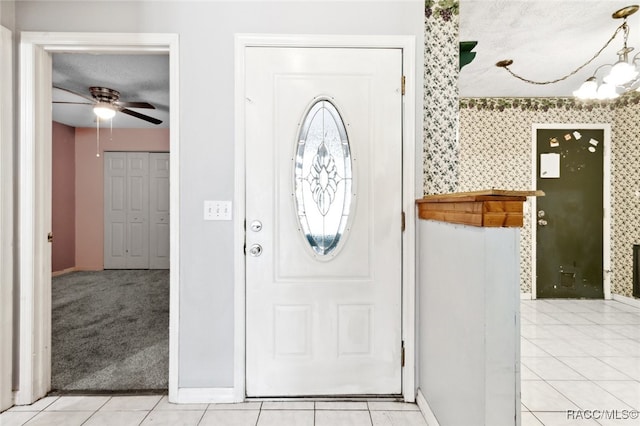 foyer with ceiling fan with notable chandelier and light tile patterned floors