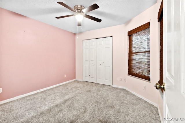 unfurnished bedroom with ceiling fan, light colored carpet, a closet, and a textured ceiling