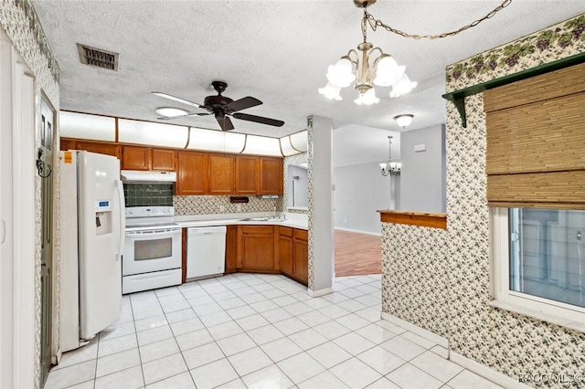 kitchen featuring white appliances, decorative light fixtures, ceiling fan with notable chandelier, and a textured ceiling