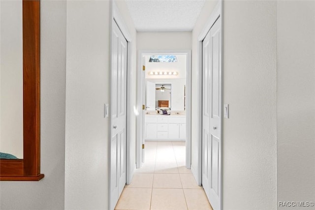 hallway featuring a textured ceiling and light tile patterned floors