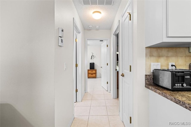 hall featuring a textured ceiling and light tile patterned flooring