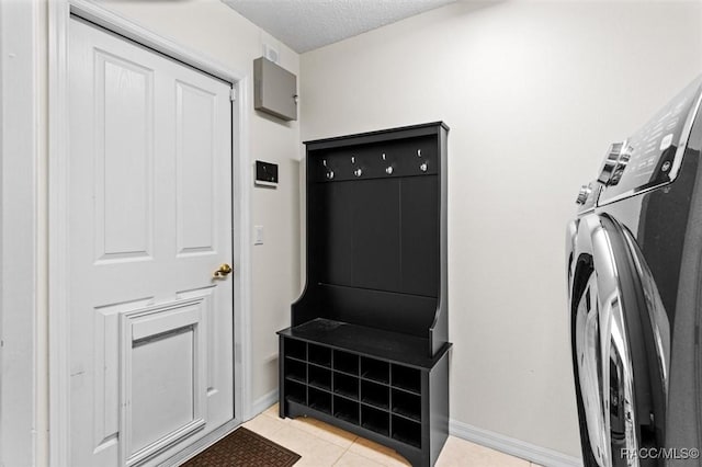 washroom with washer and clothes dryer, light tile patterned floors, and a textured ceiling