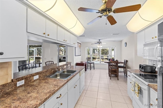 kitchen with white appliances, white cabinets, a textured ceiling, sink, and light tile patterned flooring