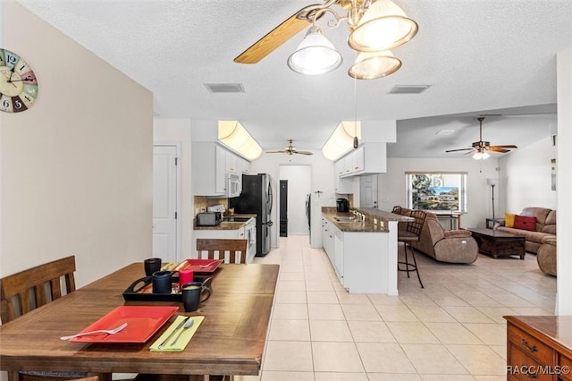 tiled dining room featuring ceiling fan, sink, and a textured ceiling