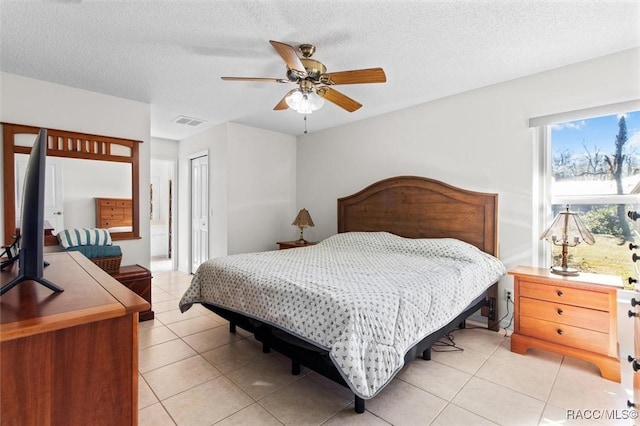 tiled bedroom with a textured ceiling, ceiling fan, and a closet