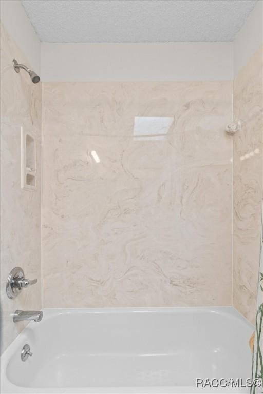 bathroom with tub / shower combination and a textured ceiling