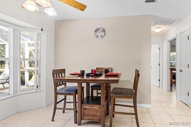 tiled dining space with ceiling fan and a textured ceiling