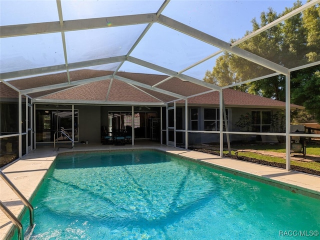 view of swimming pool featuring glass enclosure and a patio