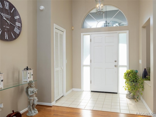 entrance foyer featuring light wood-type flooring, a high ceiling, and an inviting chandelier